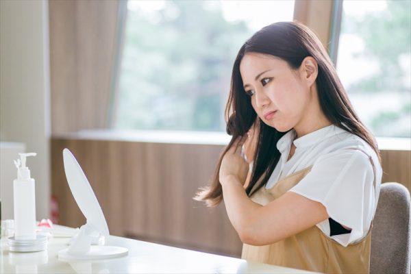 ヘアブラシをしながら悩む女性